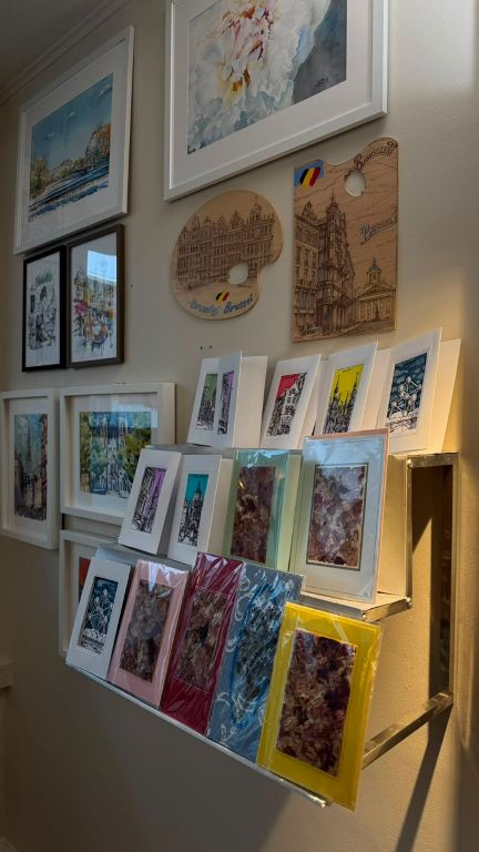 Framed watercolours of Brussels, wooden palettes and a shelf of art cards
