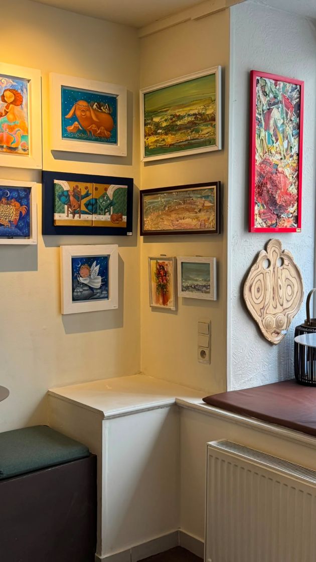 Corner of the café hung with colourful paintings and a carved wooden mask
